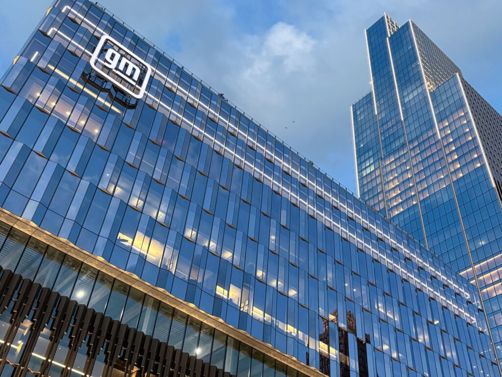 Modern skyscraper view of GM headquarters with glass facade reflecting sunset in Detroit.