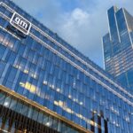 Modern skyscraper view of GM headquarters with glass facade reflecting sunset in Detroit.
