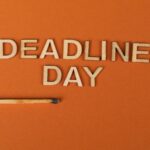 Conceptual image of a deadline with wooden letters and burnt matchstick on orange background.