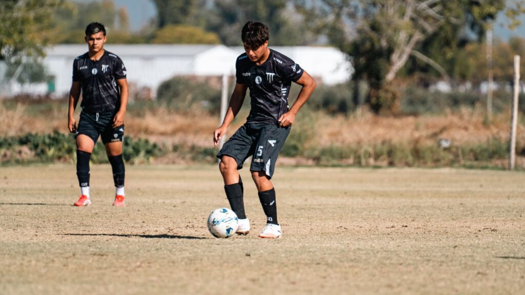 Two young male soccer players practicing dribbling skills on a sunny day.