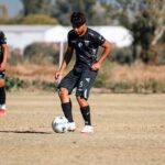 Two young male soccer players practicing dribbling skills on a sunny day.
