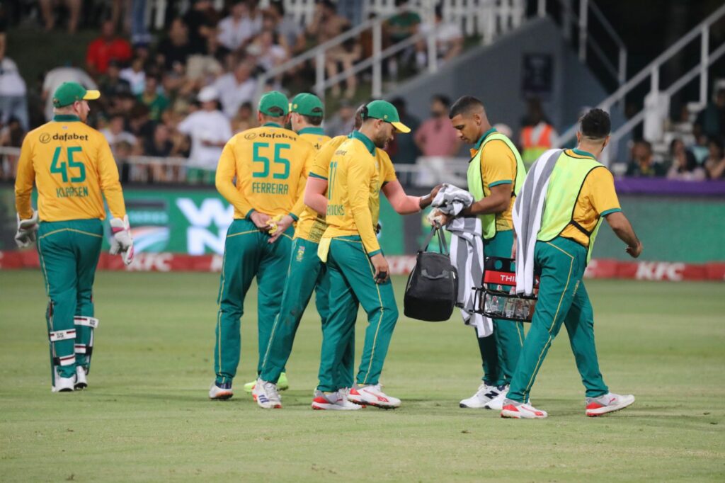 Cricket players gather on the field during a match, discussing strategy.