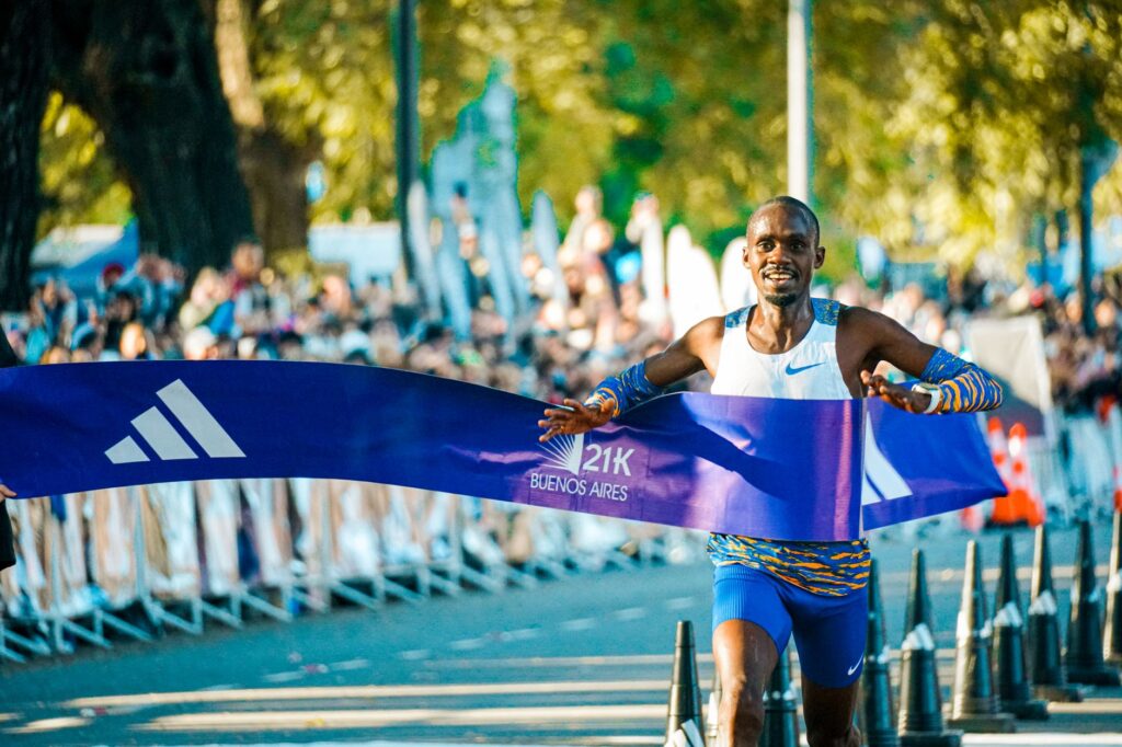 Male athlete crossing the finish line at the Buenos Aires marathon in a lively outdoor event.
