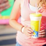 Close-up of a young woman holding a lemonade outdoors during summer.