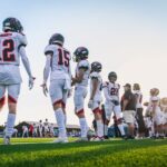 A high school football team lines up on the field, ready for their match.
