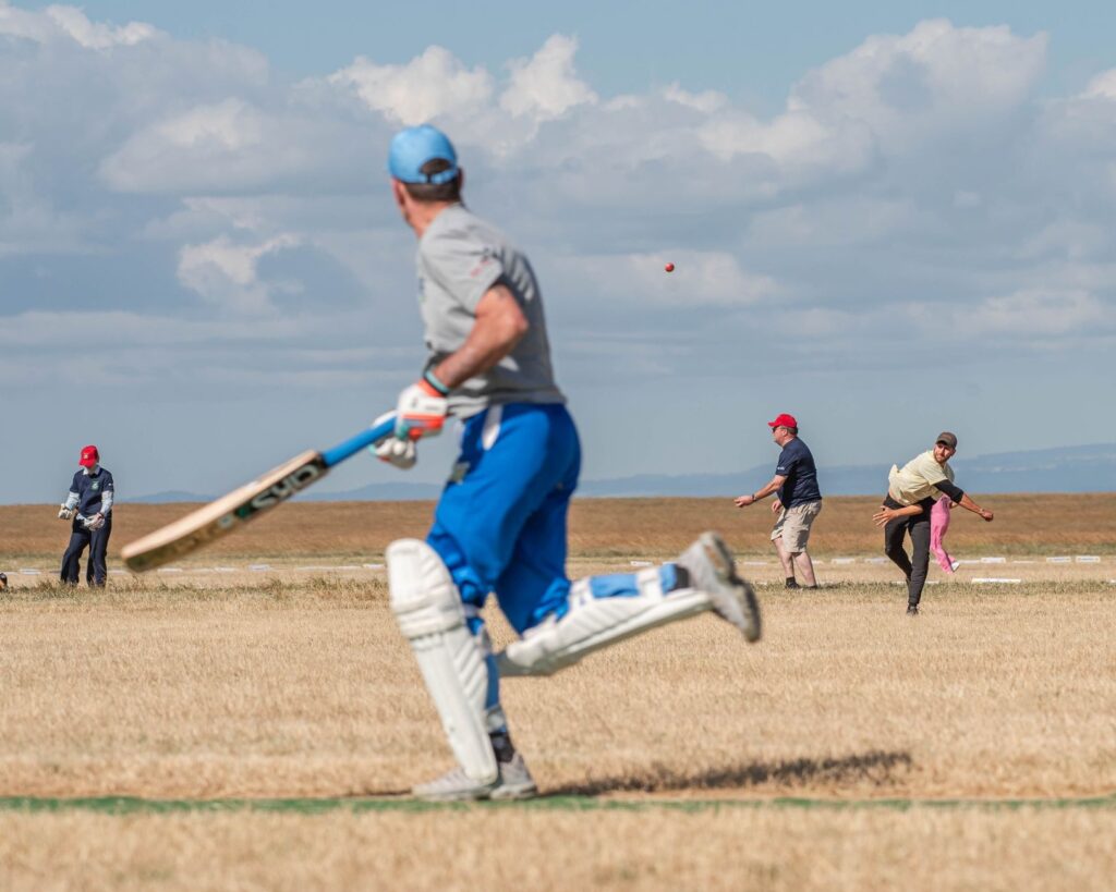 Cricketers playing a match on a sunny field with dynamic action captured.