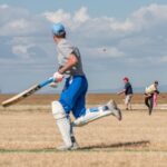 Cricketers playing a match on a sunny field with dynamic action captured.