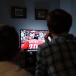 Father and son enjoying a hockey game together on TV from their living room.