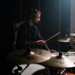 A man playing drums with headphones in a recording studio, perfect for music themes.