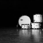 Classic black and white photo of a drum set in a dramatic, moody setting.