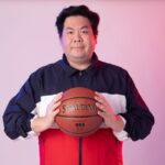 Man in sportswear with basketball against a gradient background.