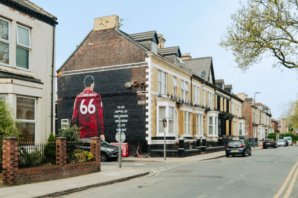 Urban street scene in Liverpool featuring a prominent mural of Trent Alexander-Arnold.