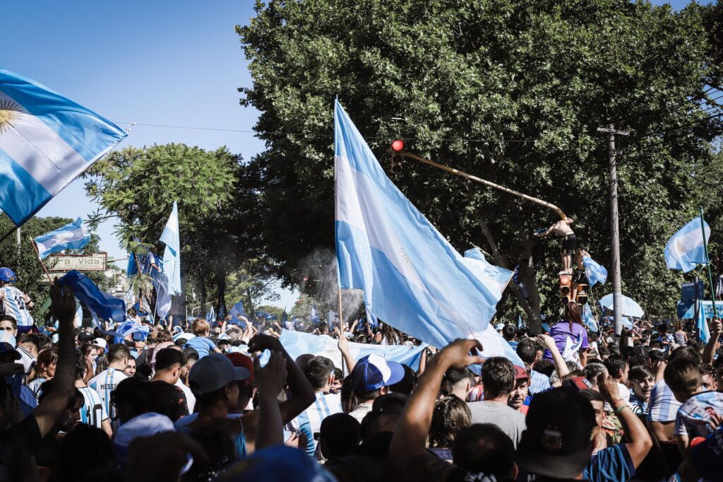 Crowd celebrating with Argentine flags in Buenos Aires during a joyful daytime event.