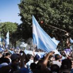 Crowd celebrating with Argentine flags in Buenos Aires during a joyful daytime event.