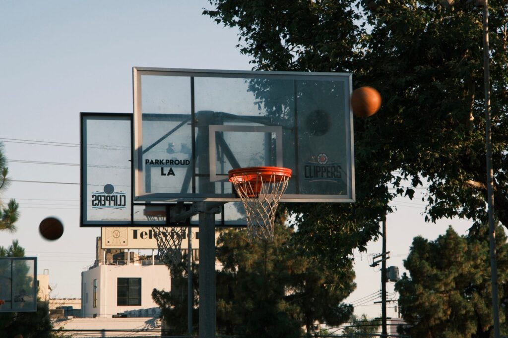 A basketball hoop on an outdoor court in Los Angeles, with trees and buildings in the background.