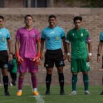Soccer team and referees in uniform standing on the field before a match.