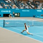 Dynamic scene of players in action at the US Open on a bright tennis court.