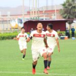 Soccer players celebrating a thrilling goal during a competitive match on a vivid green field.
