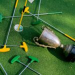 Colorful mini golf putters with a trophy on vibrant green turf, symbolizing victory.