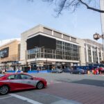 Cityscape featuring Capital One Arena in Washington D.C., bustling with people and traffic on a clear day.