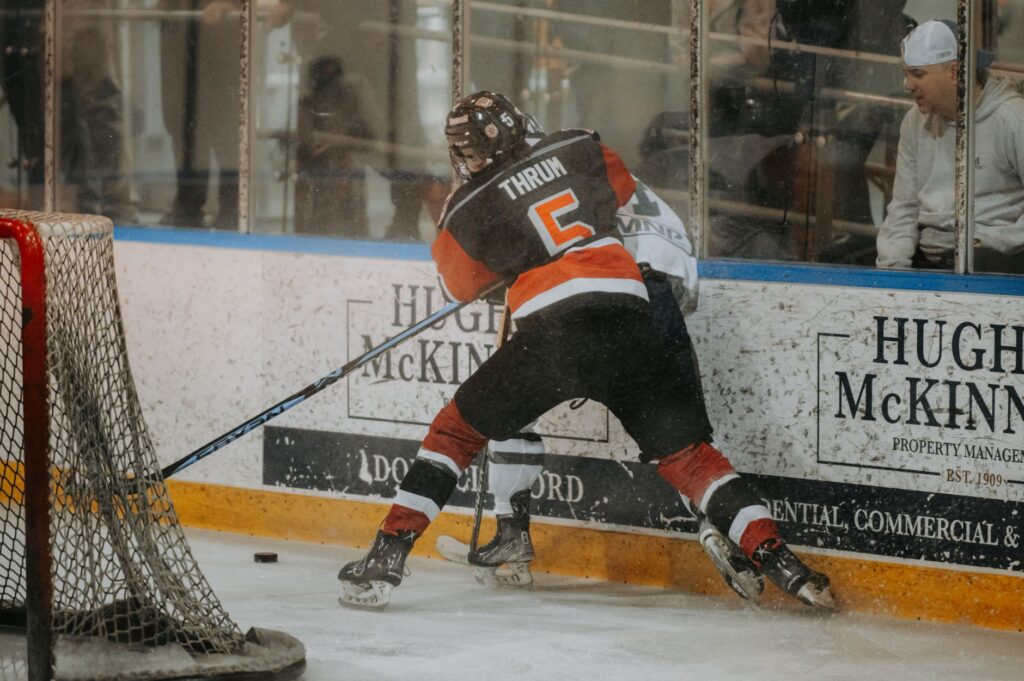 Intense ice hockey match with players clashing by the rink's boards, showcasing dynamic sports action.