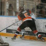 Intense ice hockey match with players clashing by the rink's boards, showcasing dynamic sports action.
