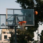 A basketball hoop on an outdoor court in Los Angeles, with trees and buildings in the background.