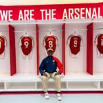Visitor in Arsenal locker room with team jerseys and club branding.