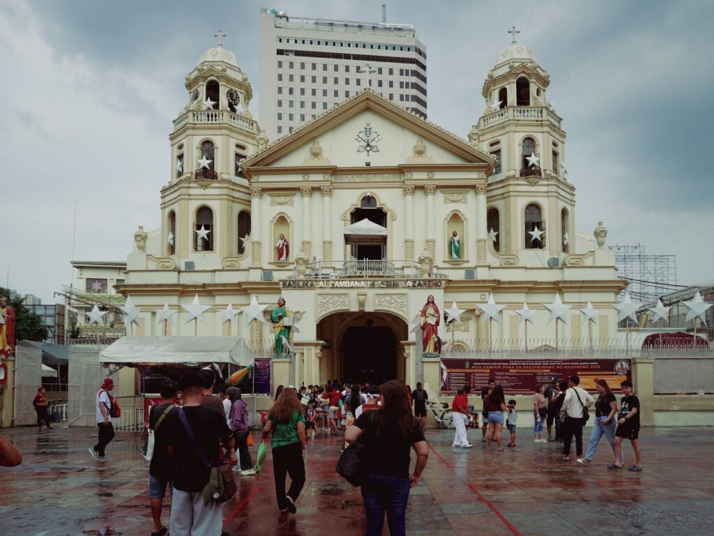 Stunning view of Quiapo Church, Manila, with visitors and a backdrop of skyscrapers.
