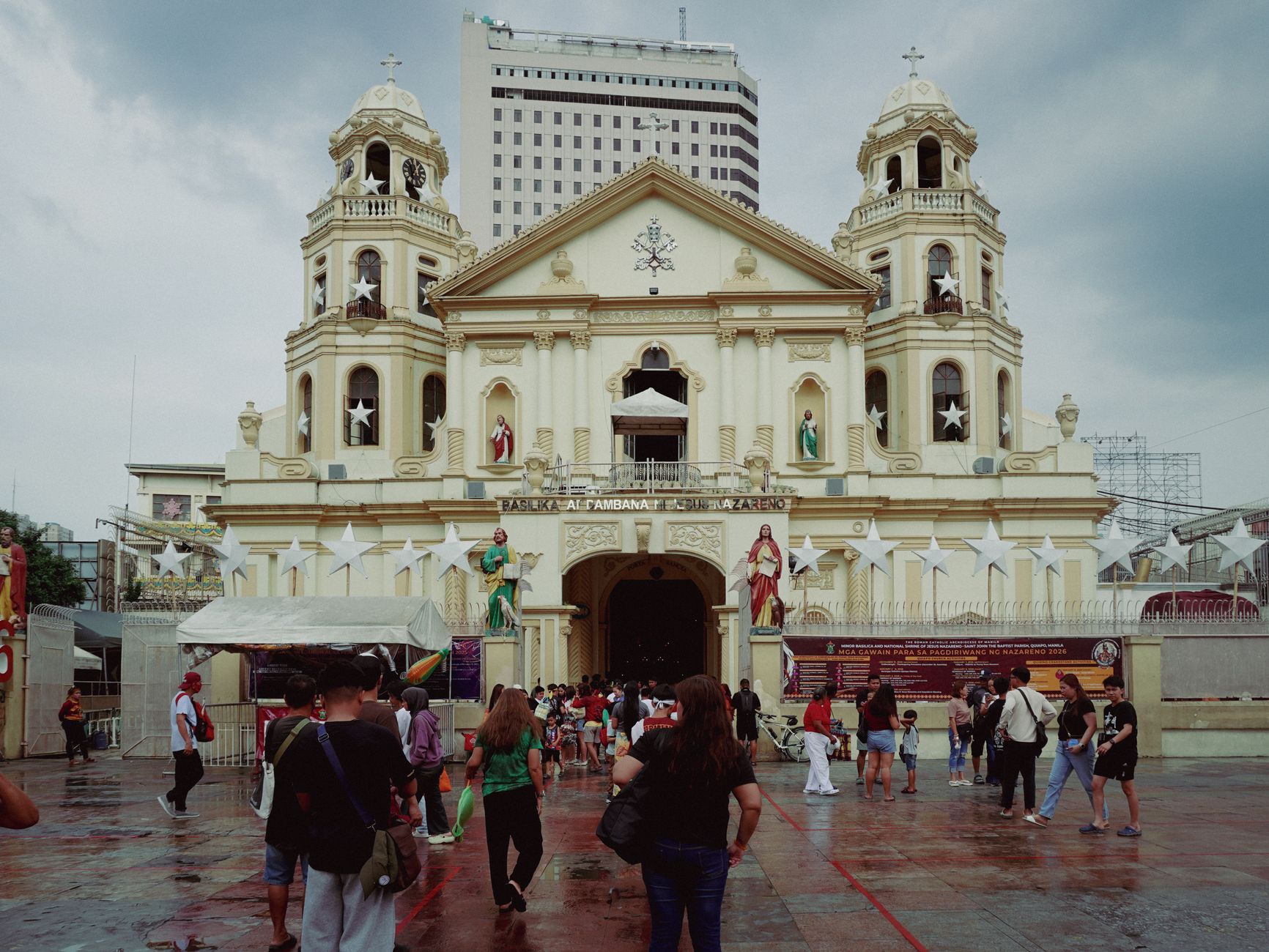 Stunning view of Quiapo Church, Manila, with visitors and a backdrop of skyscrapers.