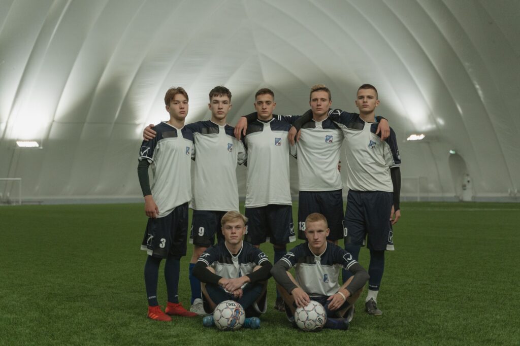 A group of young male soccer players in uniform posing on an indoor field.