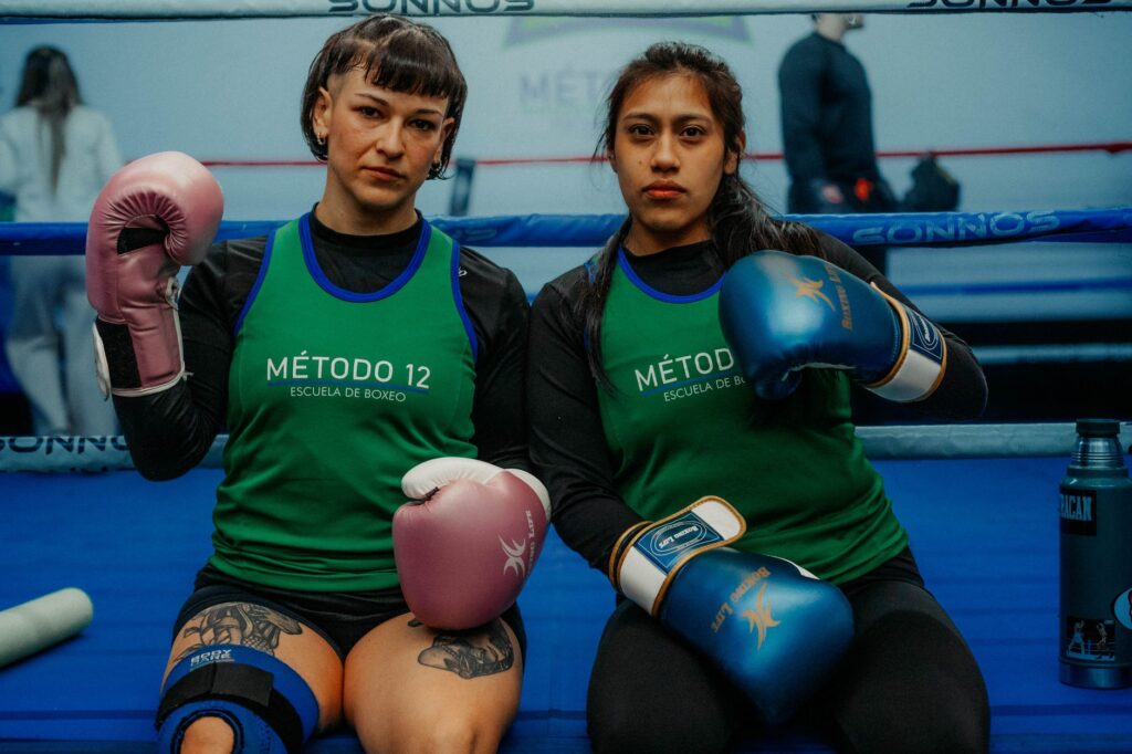Two female boxers in a Buenos Aires gym, ready for training, showcasing determination.
