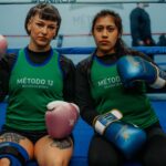 Two female boxers in a Buenos Aires gym, ready for training, showcasing determination.