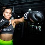A focused female boxer in action during a training session wearing boxing gloves and sportswear.