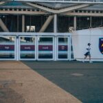 A person walking by West Ham United football stadium entrance in London.