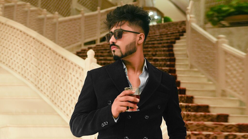 Fashionable man with sunglasses holding a drink at elegant indoor location.