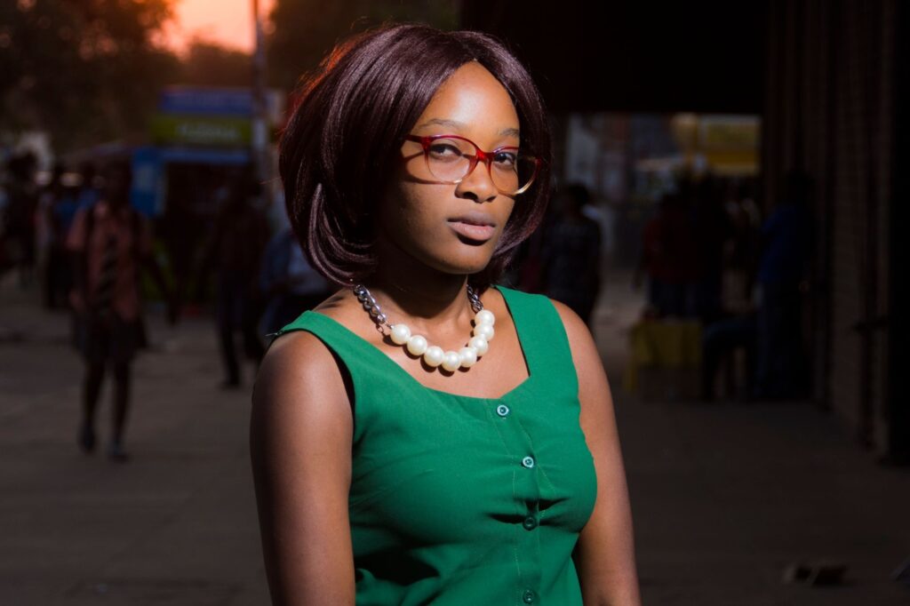 Portrait of a fashion-forward woman in a green dress and eyewear, captured on a city street at sunset.