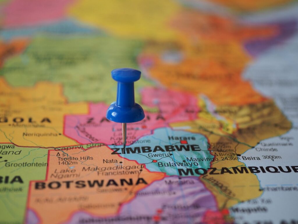 A blue pushpin marks Zimbabwe on a colorful close-up map highlighting its geographical position.