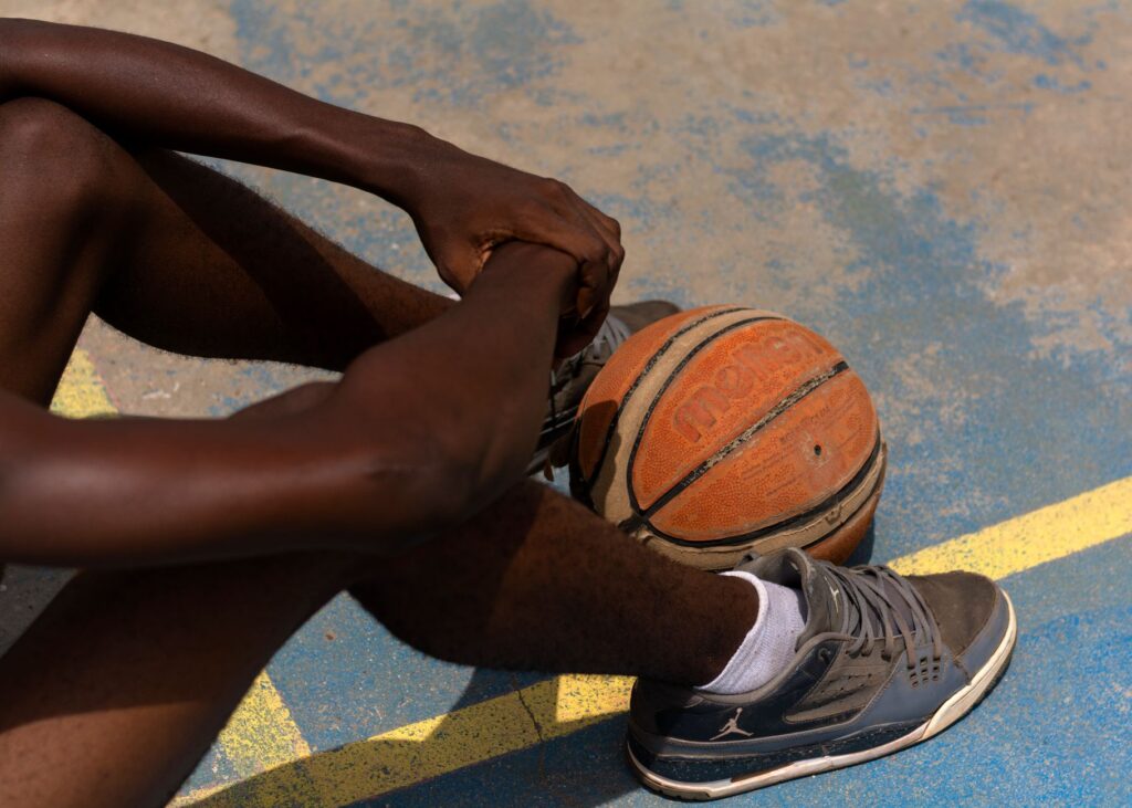 Close-up of a basketball player sitting on an outdoor court in Ado Ekiti, Nigeria.