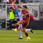 Intense action during a professional soccer match with players in motion on the field.