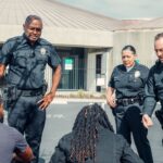 A group of police officers interact with civilians in a public outdoor setting.