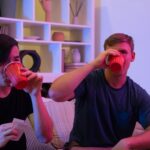 Two men having fun drinking and playing cards in a cozy indoor setting.