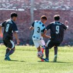 Capture of three soccer players competing for the ball during a match on a sunny day.