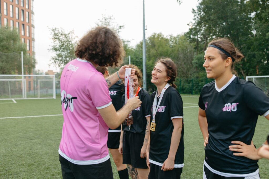 A women's football team receiving medals on the field, celebrating their victory.