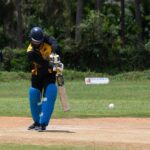 Cricketer making a powerful shot during a day game outdoors.