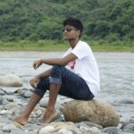 A young man sits on rocks by a river in Sylhet, Bangladesh.