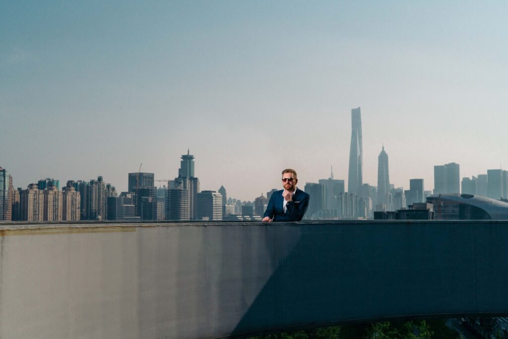 A business professional in a suit overlooking the Shanghai skyline from a rooftop.