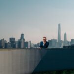 A business professional in a suit overlooking the Shanghai skyline from a rooftop.