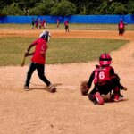 A youth baseball game in progress with kids playing on a sunny day, wearing protective gear.