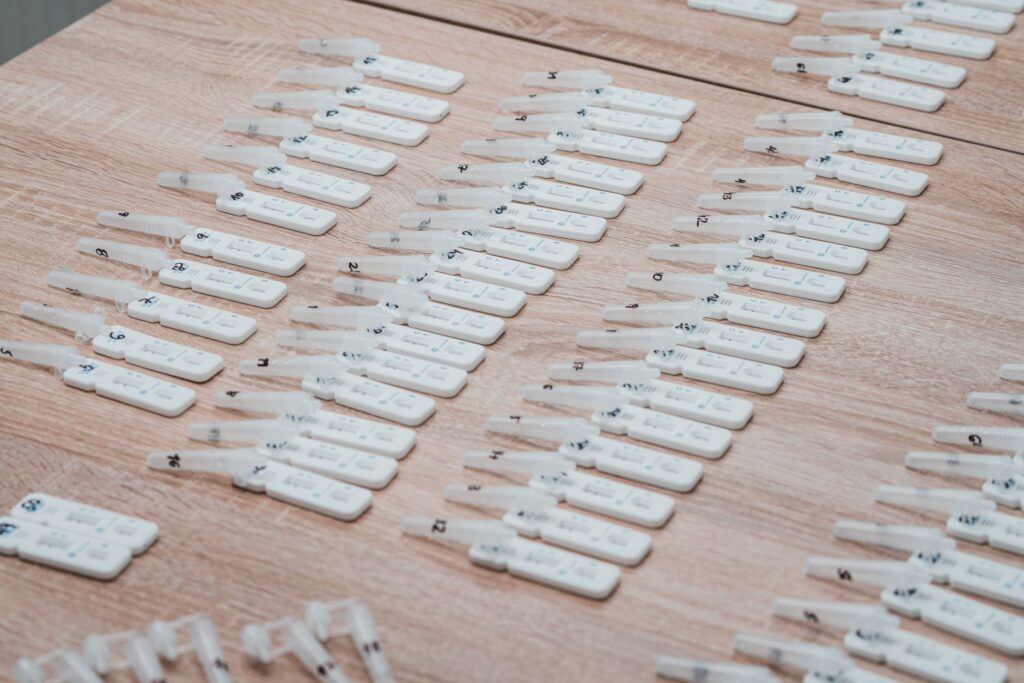 Multiple COVID-19 test kits displayed neatly on a wooden table indoors.